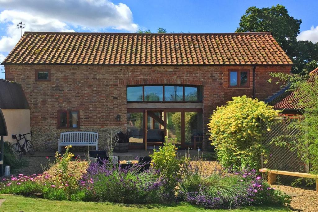 a brick house with a bench in a garden at 3 Bed in Thursford oc-1793 in Thursford