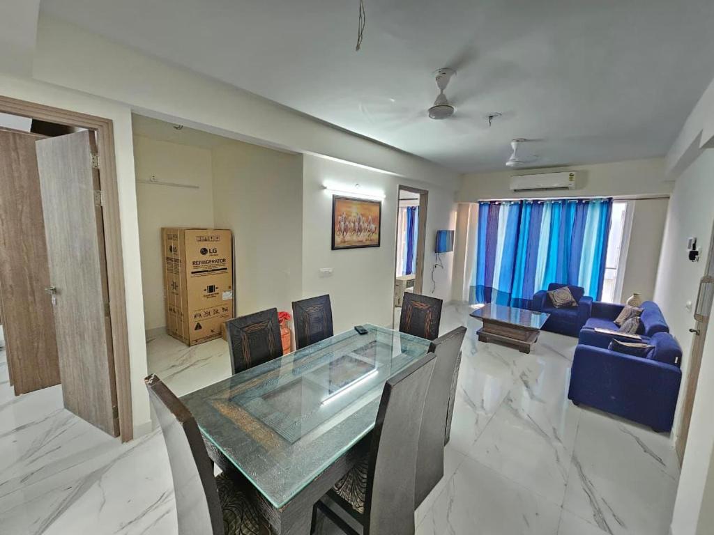 a living room with a glass table and a blue couch at Cozy corner in Gurgaon