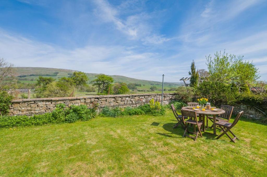 a table and chairs in a yard with a stone wall at 3 Bed in Hawes oc-s30429 in Hawes