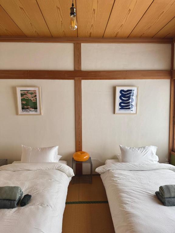 two beds in a room with white sheets at Blanco Escape in Myoko