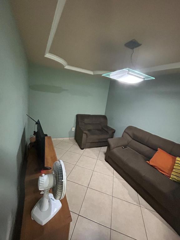 a living room with a couch and a fan at apartamento aconchego 01 in Divinópolis