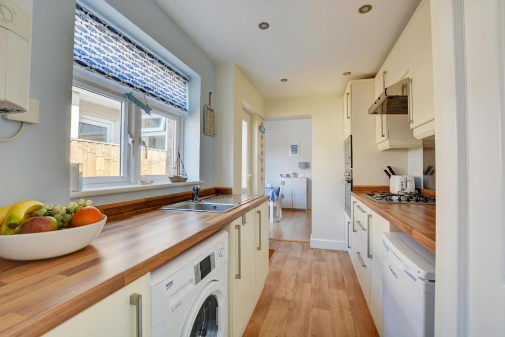 a kitchen with white cabinets and a bowl of fruit on the counter at 2 Bed in Hunstanton oc-1778 in Hunstanton