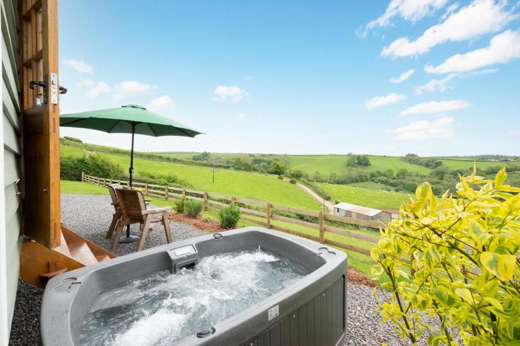 a hot tub on a patio with an umbrella at 1 Bed in Cove oc-cloudm in Bampton
