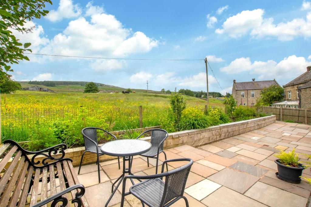 a patio with a table and chairs and a field at 4 Bed in Arkengarthdale oc-h27492 in Low Eskcleth