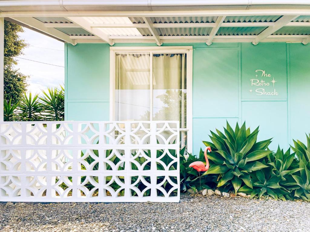 a blue house with a white gate and a pink flamingo at The ReTrO Beach Shack in Aldinga Beach