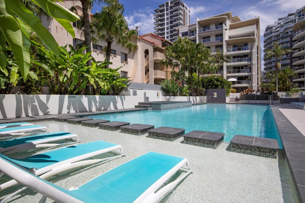 a swimming pool with chaise lounge chairs next to a building at Trilogy Surfers Paradise in Gold Coast