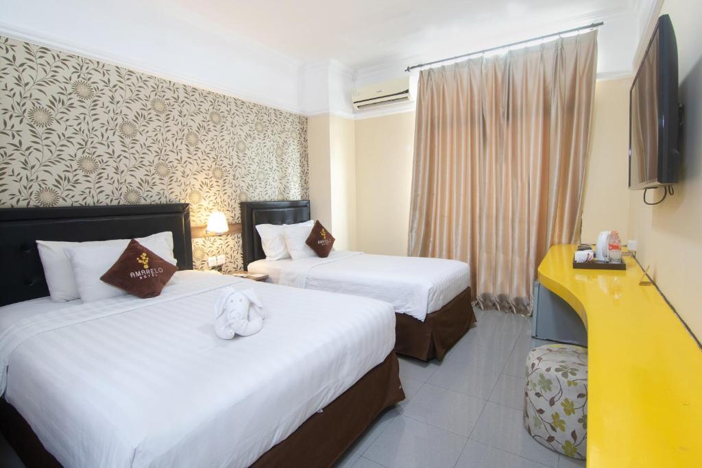a hotel room with two beds and a television at Amarelo Hotel Solo in Solo