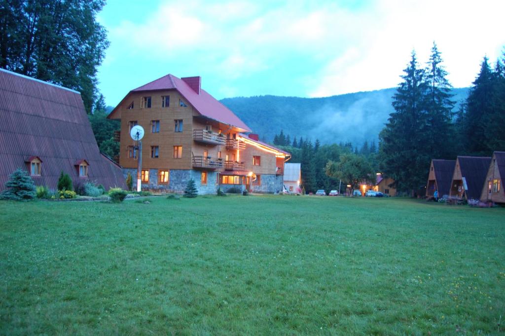 a large building in a field next to a house at Три Брати in Grebenov