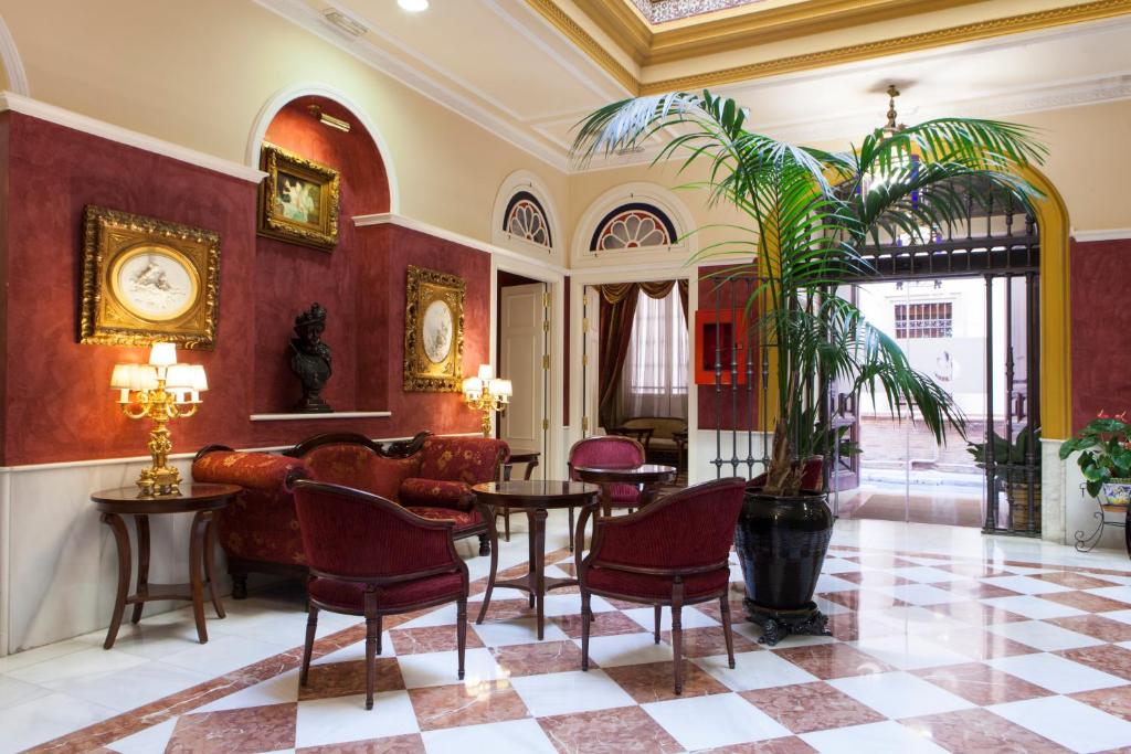 eine Lobby mit einem Sofa, Stühlen und einem Tisch in der Unterkunft Hotel Cervantes in Sevilla