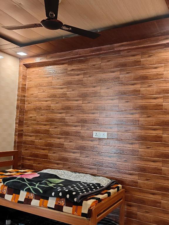 a bedroom with a wooden wall with a bed at Himalayan siddh yog ashram in Rishīkesh