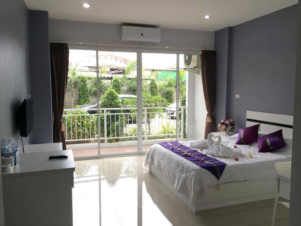 Un dormitorio con una cama con almohadas moradas y un balcón. en Pandora House by Mike Group en Pattaya North