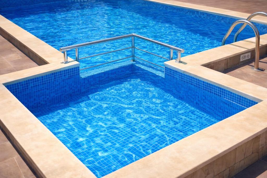 a large swimming pool with blue water at The White Houses 7 in Nesebar