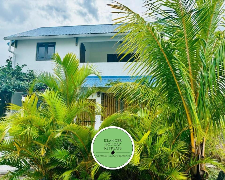 a white house with palm trees in front of it at Ti Kaséou 2 in La Gaulette