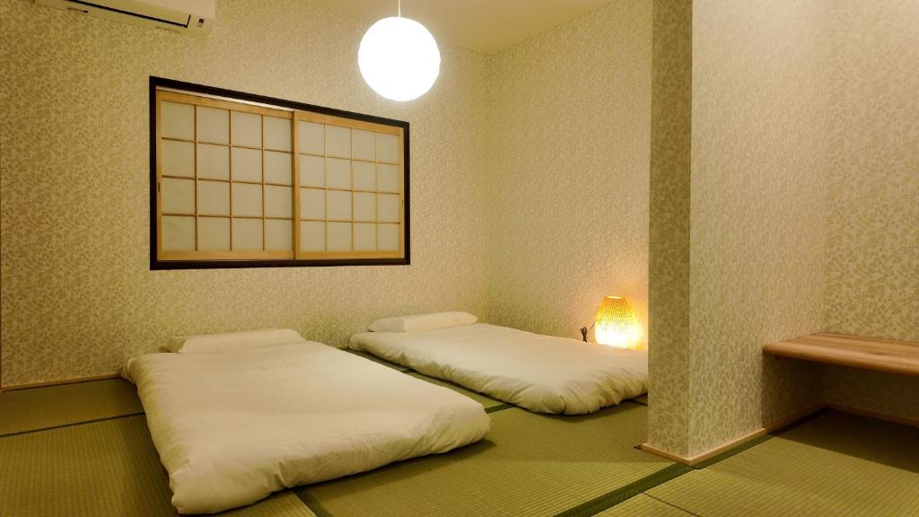two twin beds in a room with a window at 和居 琉璃 和を感じるレイアウトで心も体も休まる宿 in Wada