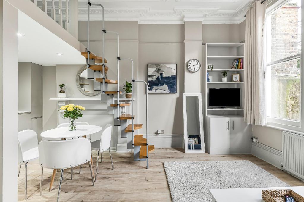a living room with a staircase and a table and chairs at Well Appointed Garden Condo in Kensington Olympia in London
