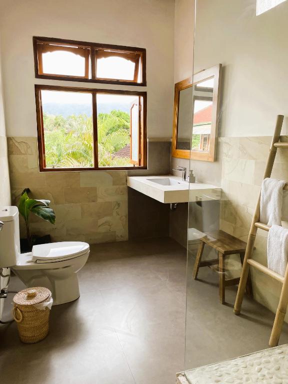 a bathroom with a toilet and a sink and a window at Kubu Elsa Bali in Lovina
