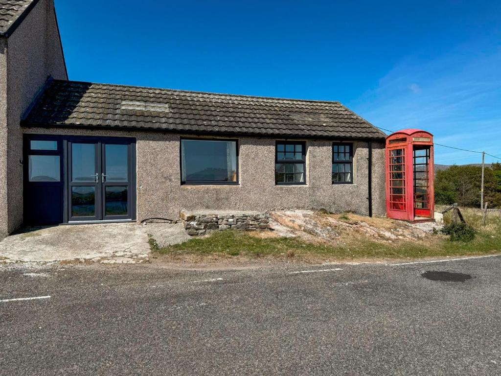 a house with a red phone booth in front of it at Post Office Lodge in Manish