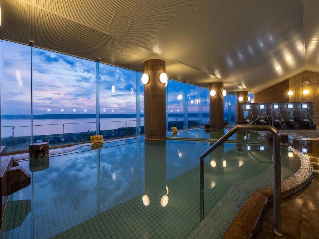 a large swimming pool with a view of the ocean at KAMENOI HOTEL Itako in Itako