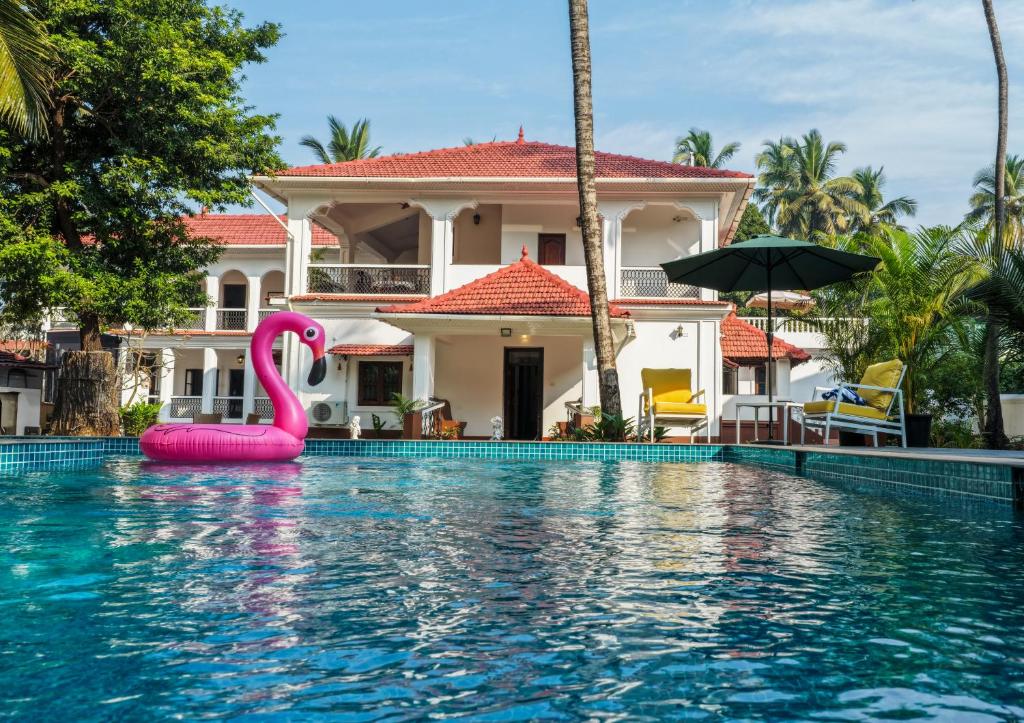 a swimming pool with a pink swan in front of a house at Quinta da Praia by Semper Felix in Calangute