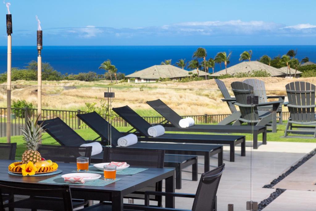 a patio with tables and chairs and the ocean at ❤PiH❤ Hale Kailani Heated Private Pool Spa in Waimea