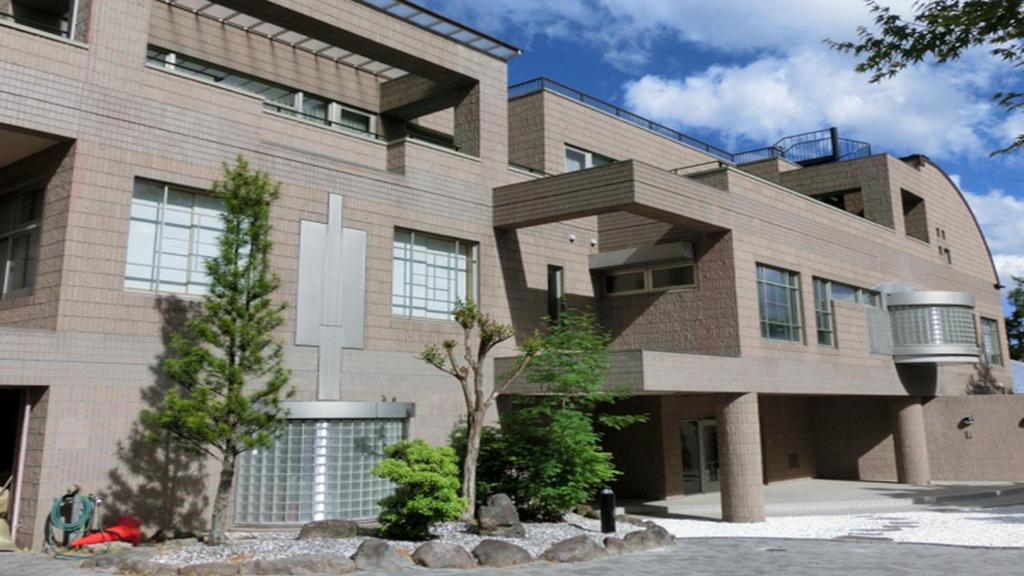 a large brick building with trees in front of it at Livemax Resort Yatsugatake Kogen in Hokuto