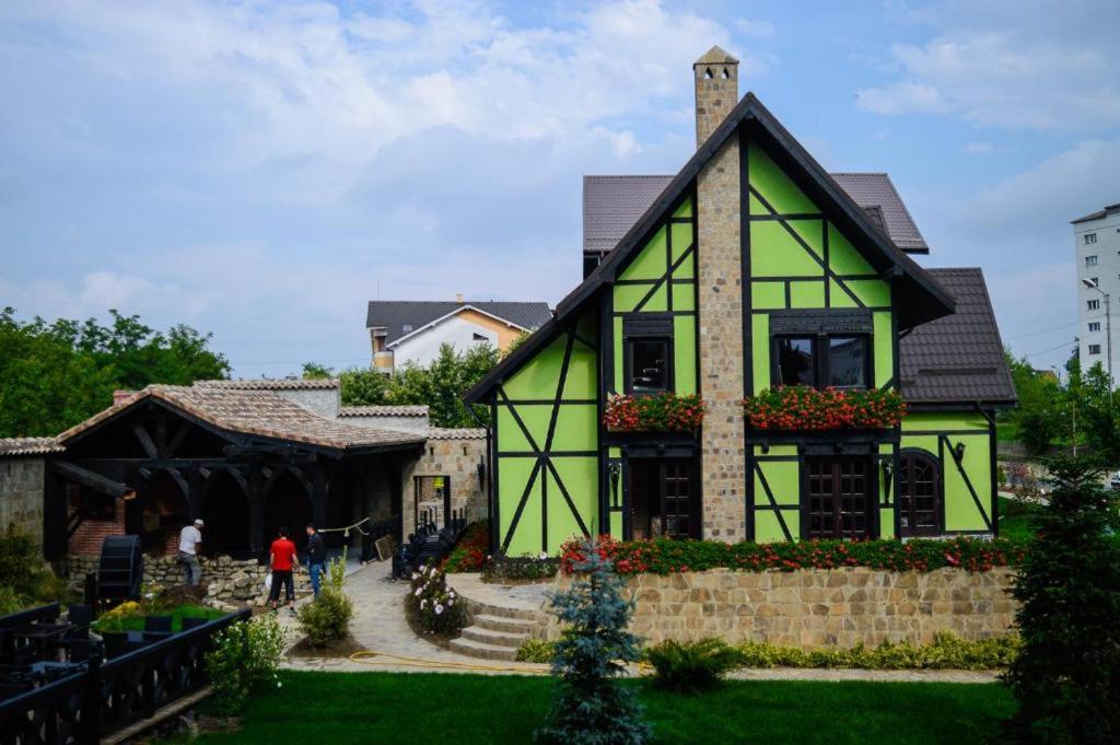 a green and white house with a building at Vila Antanta Podu' Cu Lanturi in Bacău