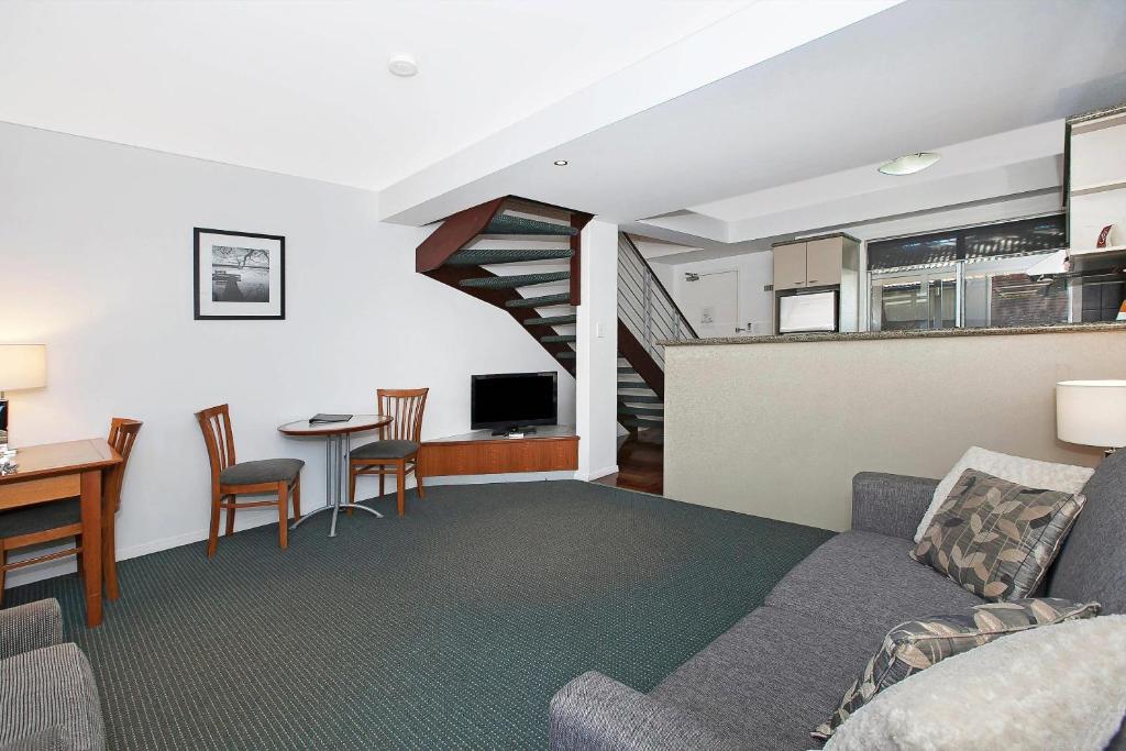 a living room with a couch and a table with chairs at Comfort Inn & Apartments Northgate Airport in Brisbane