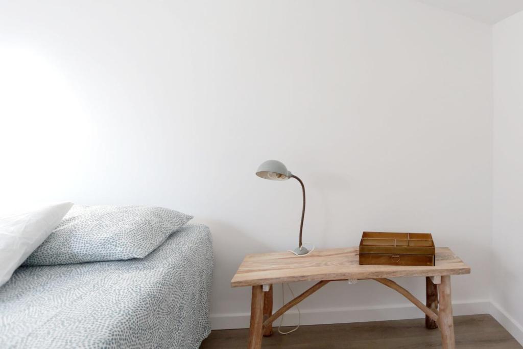 a lamp on a wooden table next to a bed at mansarda fronte mare in Potenza Picena