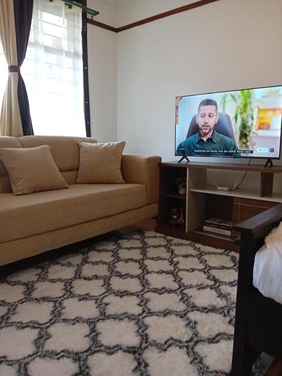 a living room with a couch and a flat screen tv at Belaire BnB Ruaka 1 in Nairobi