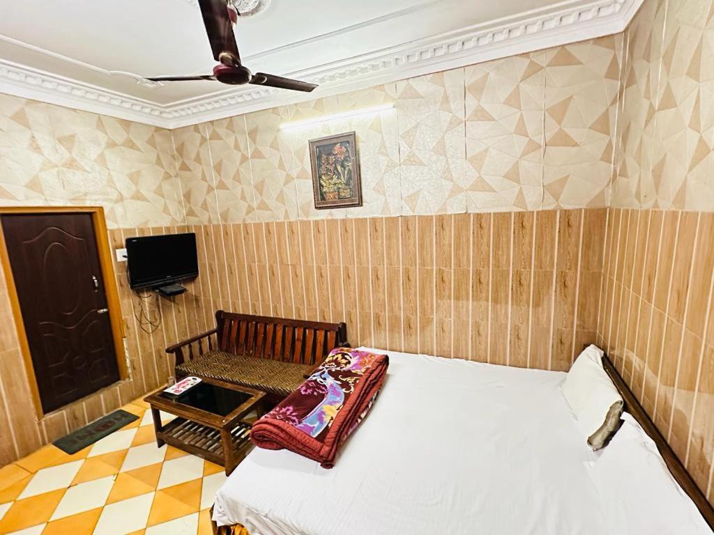 a bedroom with a bed and a chair and a tv at Hotel New Lucknow in Lucknow