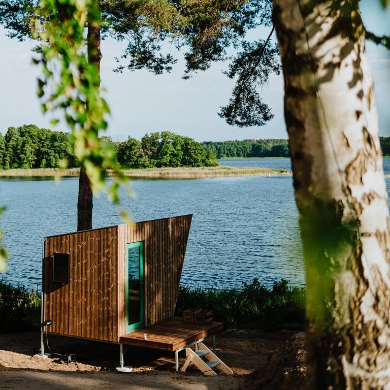 a tiny house sitting on the shore of a lake at Tiny Houses Klein Ahoi Camp Canow in Wustrow