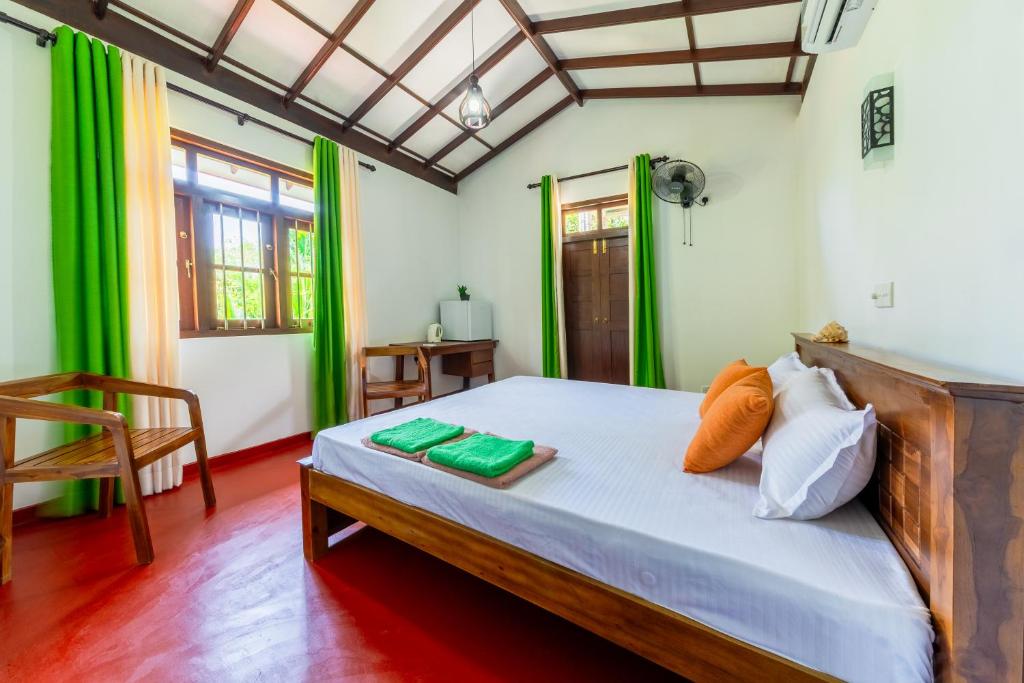 a bedroom with a bed with green curtains at Kataliya Villa in Ahungalla
