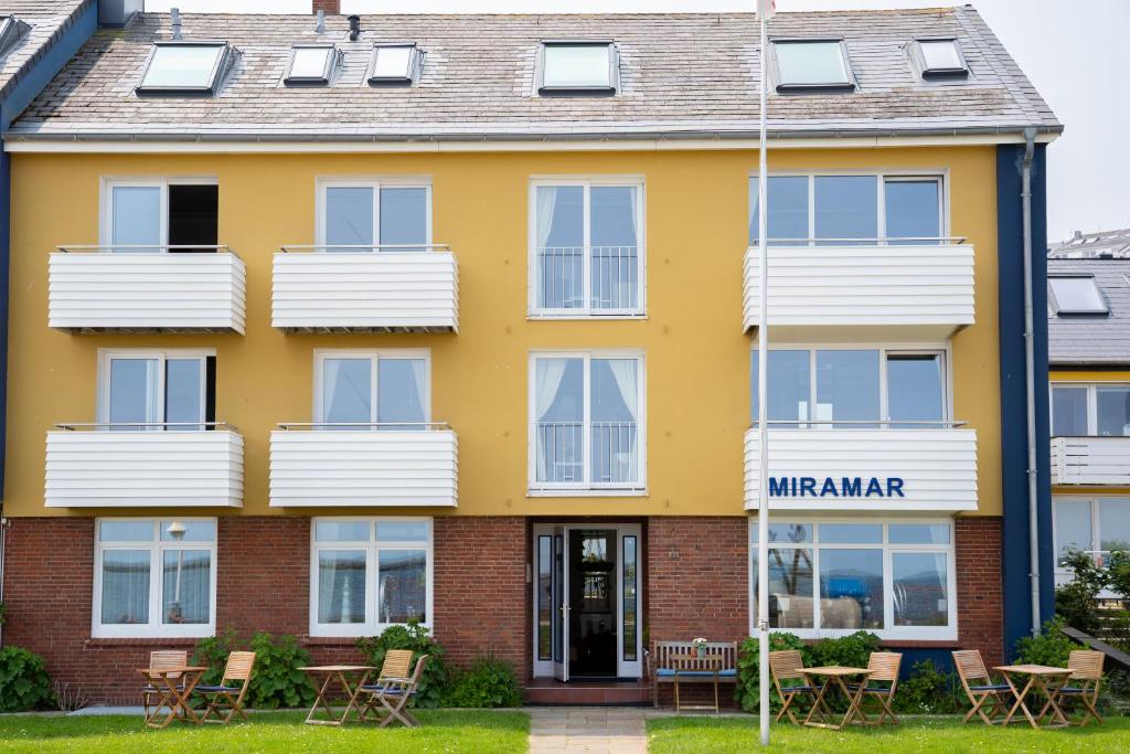 a yellow building with chairs in front of it at Miramar in Helgoland