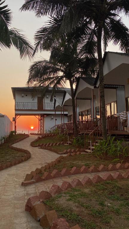 a building with palm trees in front of the ocean at Ananas Beach Resort in Agonda