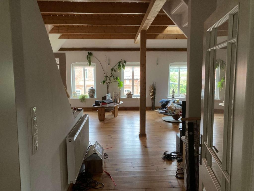 a living room with wooden floors and a room with windows at Ferienwohnung Achelpöhler in Hagen im Bremischen