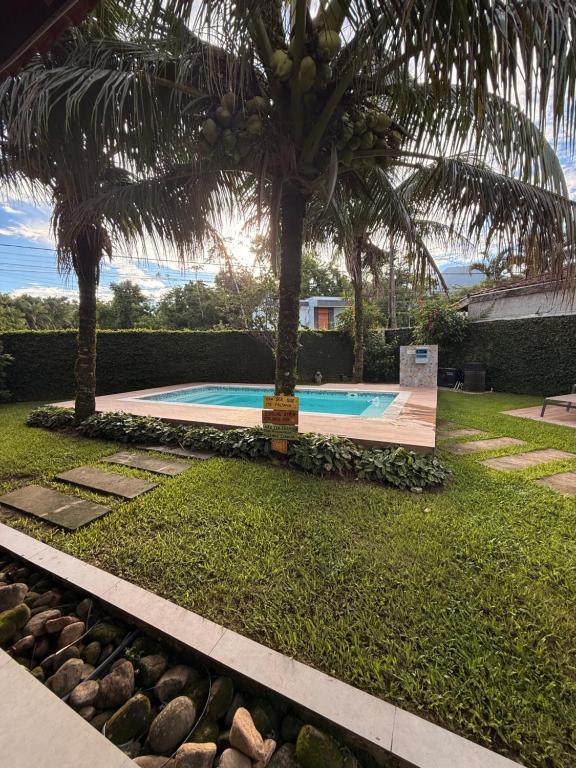 a swimming pool with a palm tree in a yard at Casalapraia in Caraguatatuba