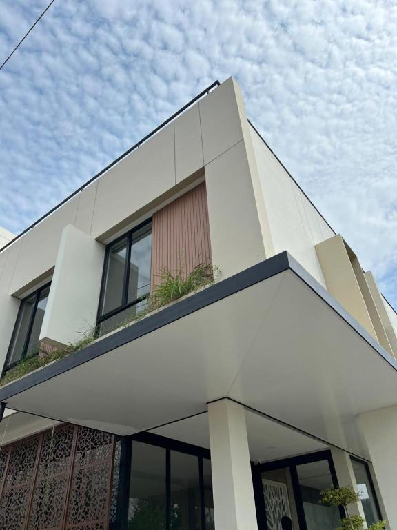 a white house with a balcony on top of it at Pavo Guest House in Minangkabau International Airport
