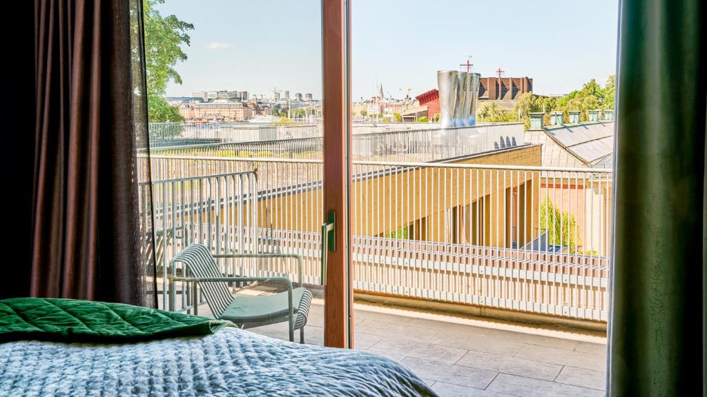 a bedroom with a bed and a balcony with a view at Backstage Hotel Stockholm in Stockholm