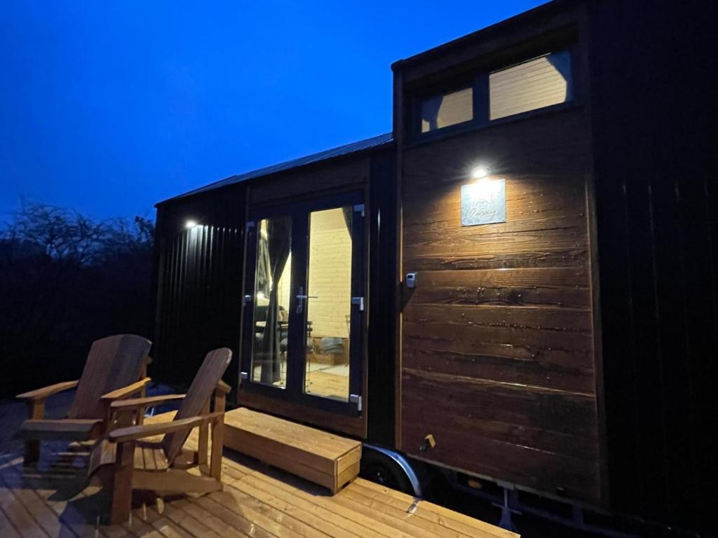 a tiny house with two chairs on a deck at Badgers Hollow by Tiny Away in Whitchurch