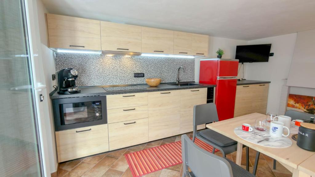 a kitchen with a table and a red refrigerator at Casa CarMa - Relax & Comfort a Cala Gonone in Cala Gonone