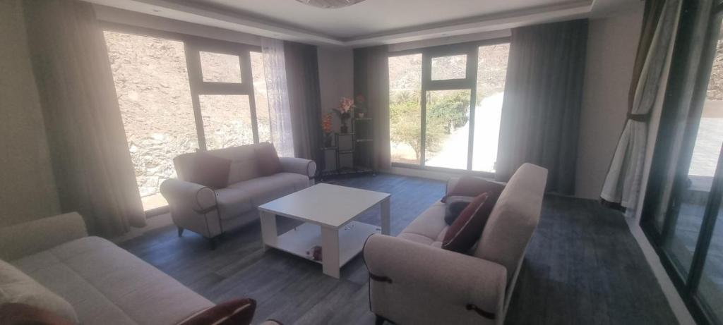 a living room with couches and a table and windows at Dareen Resort 1 in Bahlāʼ