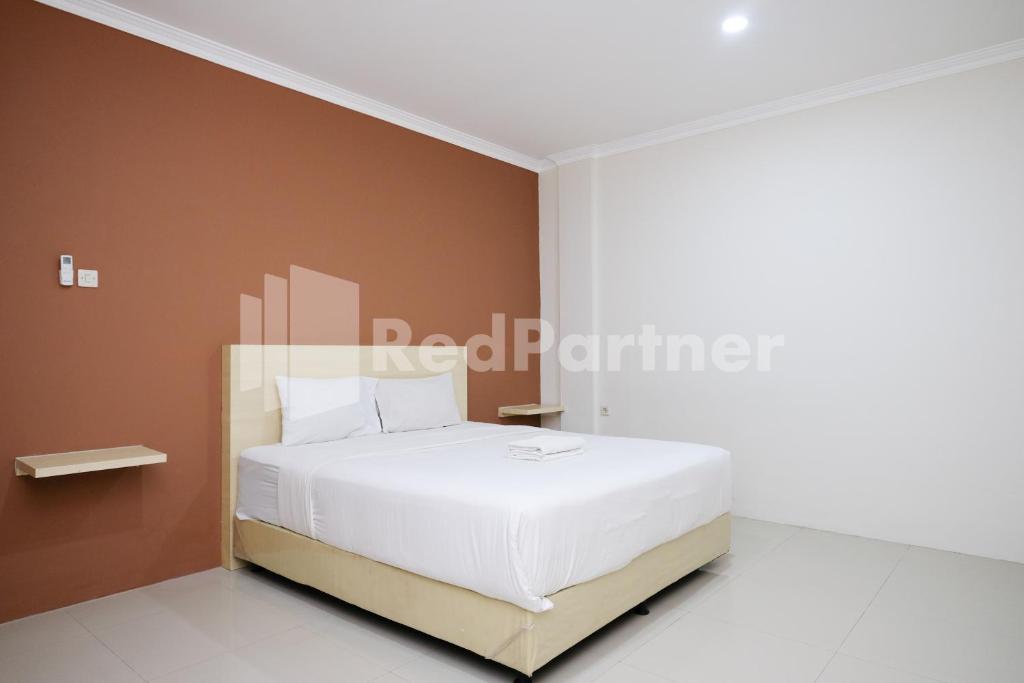 a bedroom with a white bed with brown walls at Hotel Andono near YIA Mitra RedDoorz in Yogyakarta