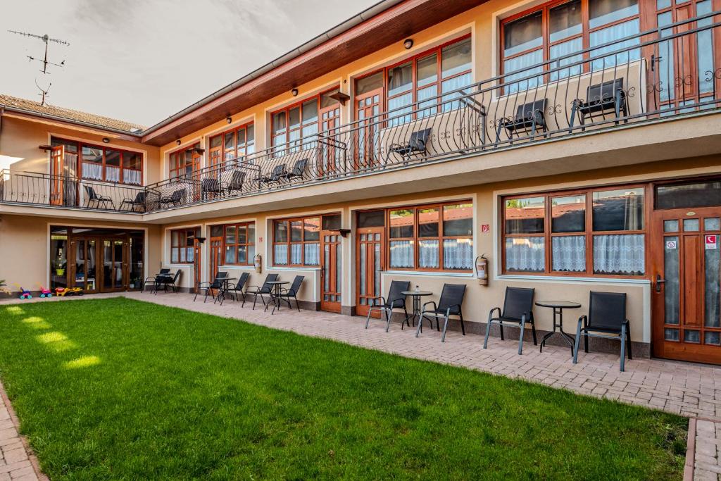 a building with chairs and a lawn in front of it at K-plus penzión in Štúrovo