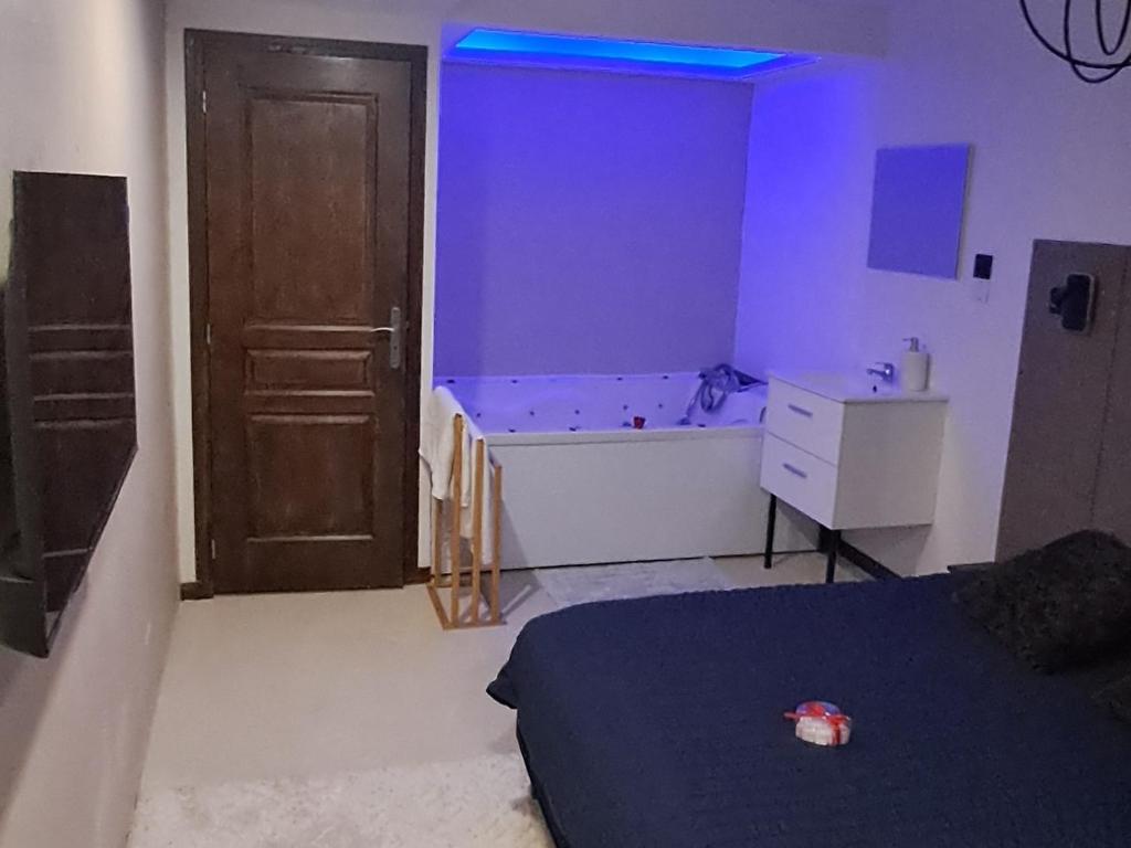 a bedroom with a bed and a tub and a door at Chambre bain balneo indépendante in Valréas
