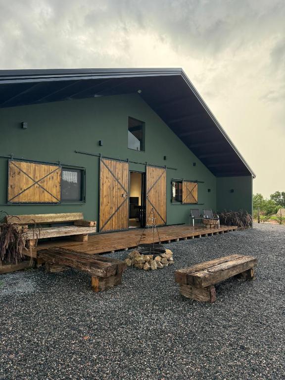 a green building with wooden doors and benches in front at Rancho Mavi Hospedagem Colônia Witmarsum in Palmeira