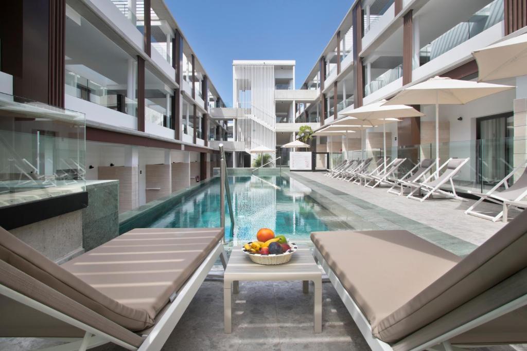 a swimming pool with a bowl of fruit on a table next to a building at Hotel Coral Cotillo Reef in El Cotillo