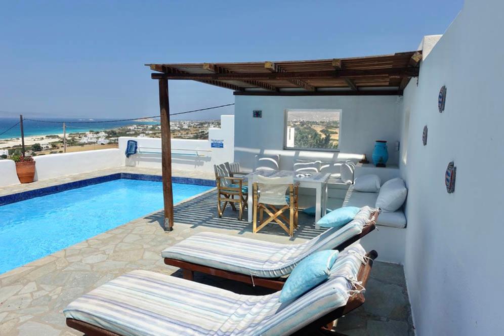 a patio with a table and chairs next to a pool at Villa H - Kamari Village in Kastraki