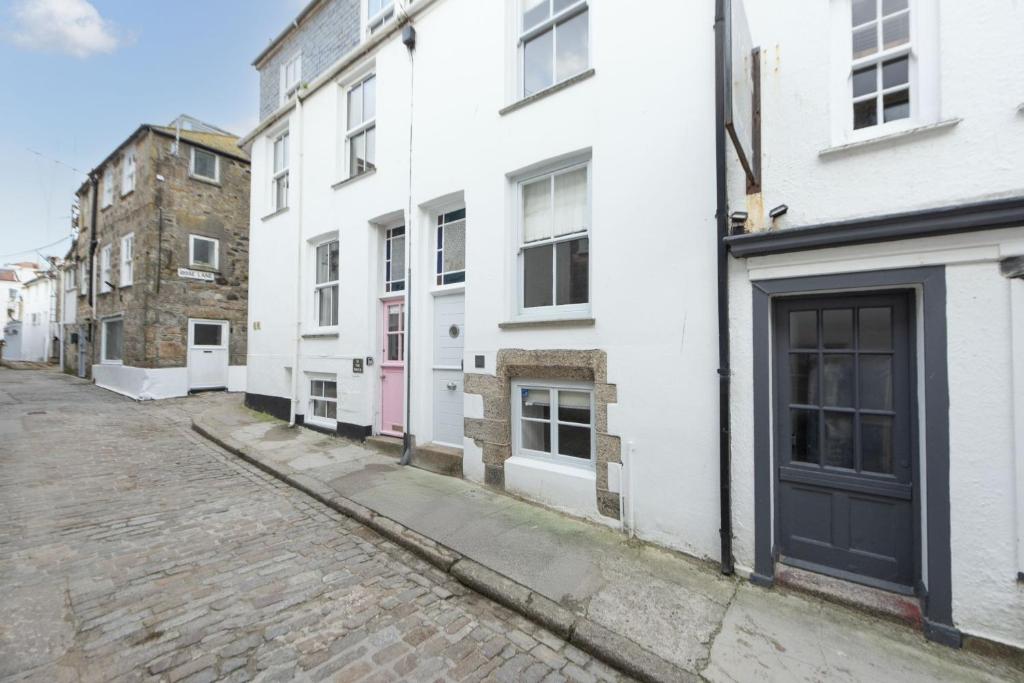 an empty street with white buildings and a black door at Walters on The Digey - 100m to beach - pets allowed in St Ives