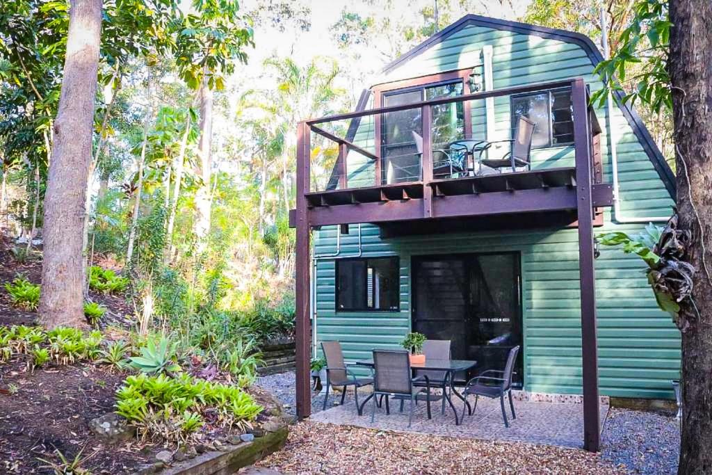 a green house with a deck with a table and chairs at GREEN TREES CHALET Australia Zoo close by in Landsborough