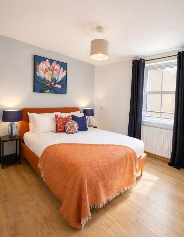 a bedroom with a large bed with an orange blanket at The Inver Nest in Inverness